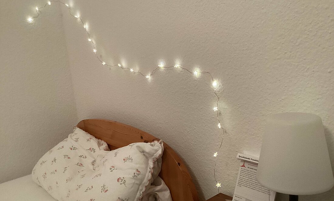 Auf dem Foto ist eine Lichterkette über dem Bett zu sehen. 