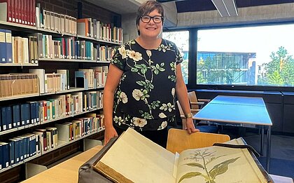 Die Historikerin Dr. Teresa Schröder-Stapper (Foto: Valeska Ridzewski) Auf dem Foto sind die Hände der Historikerin Dr. Teresa Schröder-Stapper zu sehen, die eine Tabak Pflanze in einem Buch zeigt (Foto: Valeska Ridzewski)