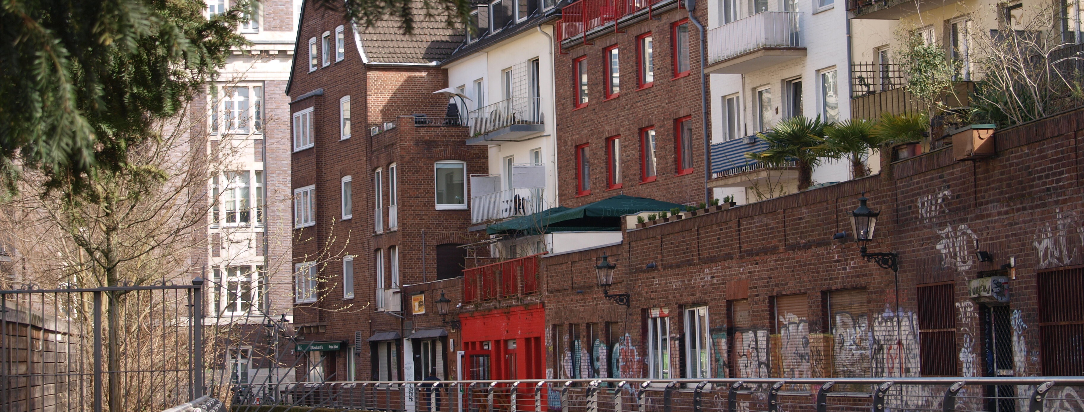 Auf dem Bild ist die Josef Wimmer-Gasse in Düsseldorf zu sehen mit ihren Backsteinhäusern und bunten Akzenten (Foto: Michelle Pieczyk)