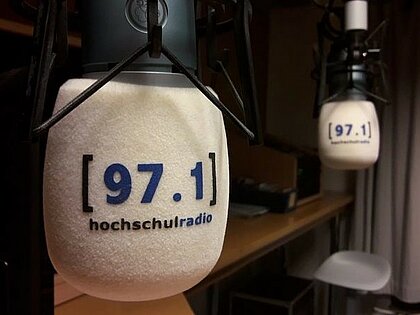 In einem Radiostudio hängen zwei Mikrofone gegenüber. Auf beiden steht 97.1 hochschulradio.