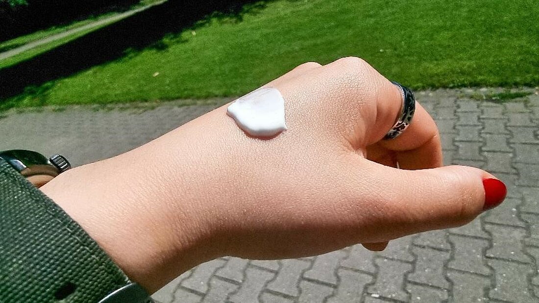 Man sieht etwas Sonnencreme auf einem Handrücken