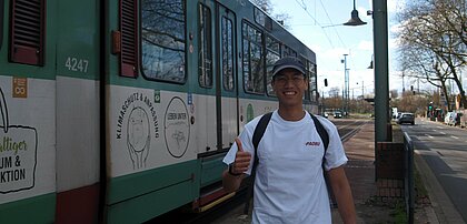 Auf dem Foto sieht man Oscar Cheong neben der U75 am Neusser Hauptbahnhof