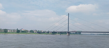 Auf den Bild ist die Oberkassler-Brücke zu sehen, die über einen Fluss verläuft. 