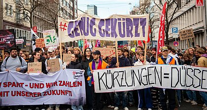 Auf dem Foto sind Demonstrierende zu sehen. Sie halten Banner und Plakate hoch