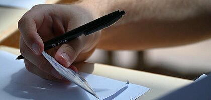Auf dem Bild sieht man eine Person, die einen Studierendenausweis hält und einen Stift. Es ist im Rahmen der SP-Wahl 2025 entstanden (Foto: Andreas Meske)
