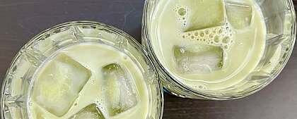 Auf dem Bild sieht man zwei Gläser gefüllt mit grünem Matcha Tee und Eiswürfeln